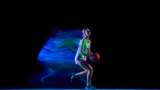 Female basketball player preparing to shoot in neon blue motion. Concept of coaching visuals, fitness product ads, motivation content, and modern training campaigns.