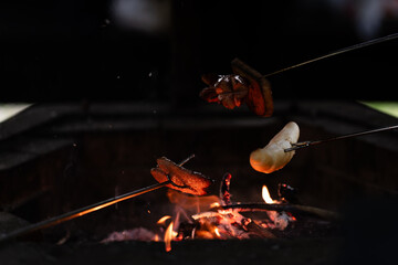Fireplace with burning fire and roasting sausages