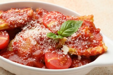 Delicious ravioli with tomato sauce, cheese and basil in baking dish on light table, closeup