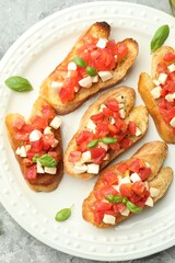 Tasty bruschettas with mozzarella cheese, tomatoes and basil on grey textured table, top view