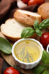 Tasty baguette served with oil, tomatoes and basil on wooden table, closeup