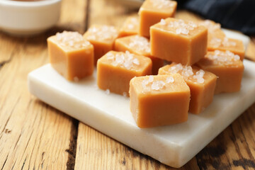 Tasty caramel candies with salt on wooden table, closeup