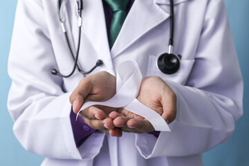 A doctor is holding a lung cancer ribbon on an isolated background