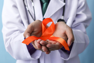 A doctor is holding a leukemia or kidney cancer ribbon on an isolated background