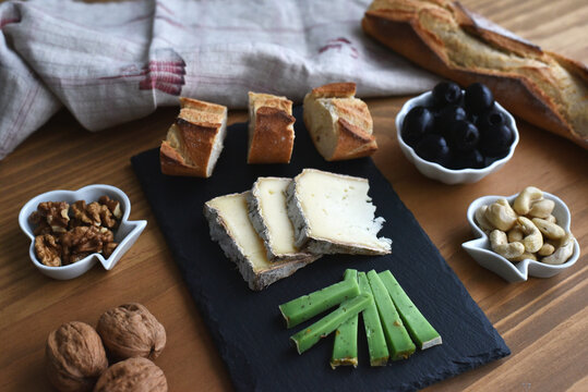 Aperitiv plate with cheese variations bread olives nuts on wooden table
