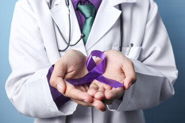 A doctor is holding a pancreatic or a testicular cancer ribbon on an isolated background