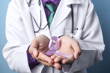 A doctor is holding a pancreatic or a testicular cancer ribbon on an isolated background