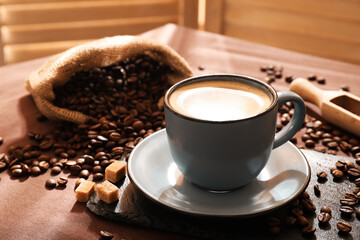 Aromatic coffee in cup, beans and brown sugar on table, closeup