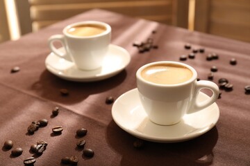 Aromatic coffee in cups and beans on table, closeup