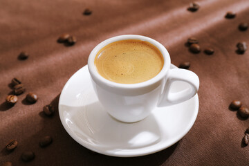 Aromatic coffee in cup and beans on table, closeup