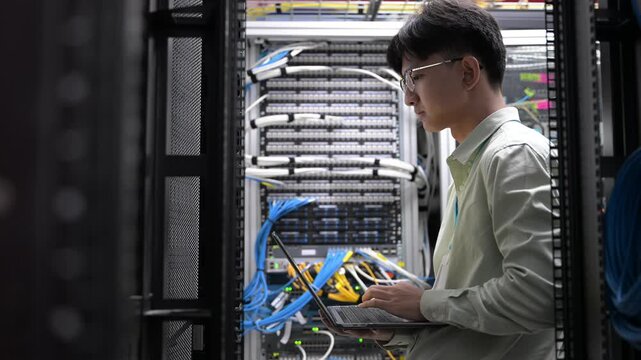 Computer engineer is setting up network in server room,Systems Maintenance Technician,Male engineer working in server room at modern data center