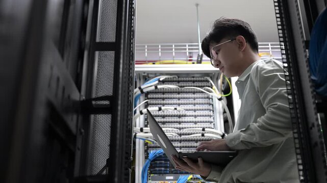 Computer engineer is setting up network in server room,Systems Maintenance Technician,Male engineer working in server room at modern data center - Powered by Adobe