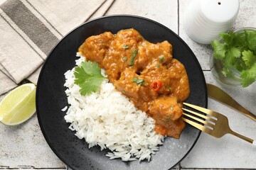 Chicken tikka masala with rice served on light tiled table, flat lay