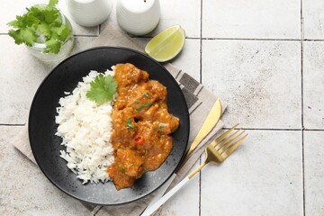 Chicken tikka masala with rice served on light tiled table, flat lay. Space for text