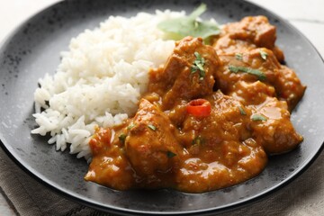 Chicken tikka masala with rice served on light tiled table, closeup
