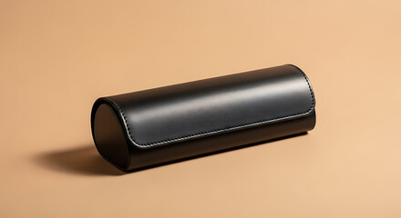 A sleek black leather cylindrical case with a hinged lid on a beige surface in a studio setting