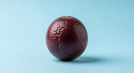A single passion fruit with wrinkled skin on a light blue background in a studio setting view close up
