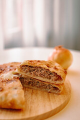 homemade golden-brown meat pie with slice cut showing rich minced filling