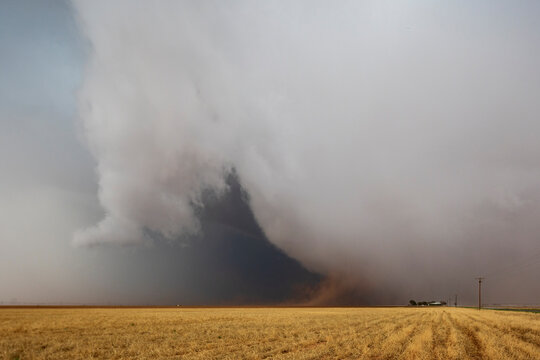 Cumulonimbus Clouds meeting the ground on the horizon, a dark shape and lighter clouds rising.
