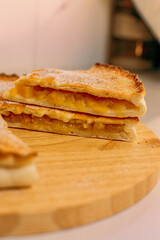 close-up of sweet apple and cinnamon pie on wooden board with a slice cut showing filling