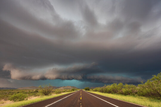 View of a road reaching the horizon, with black storm clouds above the road, the Texas Highway 90