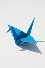 Fototapeta premium Blue origami crane bird casting shadow on white