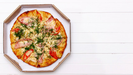 Hot delicious pizza in a box on a white wooden table, top view