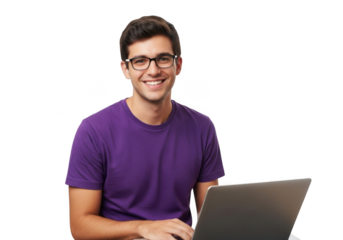A smiling young man wearing glasses and a purple t shirt works on a laptop computer against a stark black background