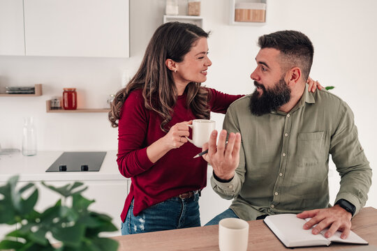 Couple discussing plans in kitchen while drinking coffee