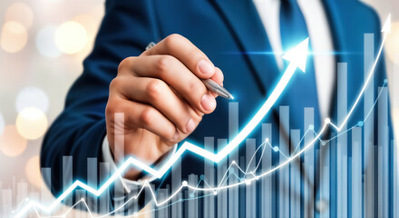 A business person drawing a rising arrow on a chart, symbolizing growth and success in the company, with a blurred background of lights and a focus on the hand and pen