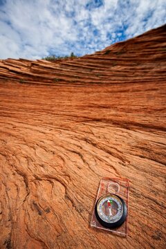 
A compass with red sandstone rock formations in the background, exploring Zion National Park