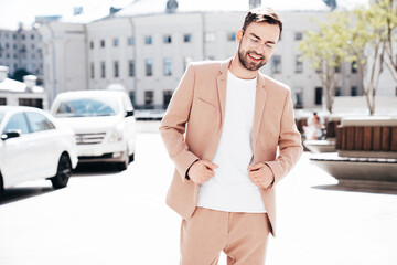 Handsome smiling stylish hipster lambersexual model. Sexy modern man dressed in elegant beige suit....