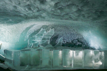 Intricate ice sculpture of a wolf and man displayed inside Glacier Paradise, Zermatt, with glacial surroundings and alpine ambiance.