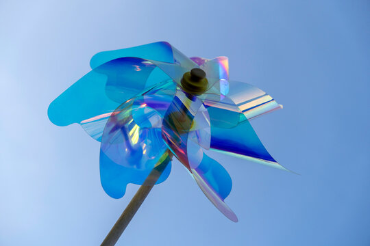 Colorful wind spinner rotates against clear blue sky on a sunny day, capturing light and attention with vibrant hues