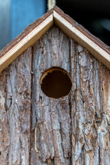 Birdhouse made of natural wood with clear entrance hole for nesting birds located in a garden setting