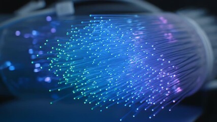 Close-up of a bundle of glowing, illuminated optical fibers emitting blue and purple light. The strands are tightly bundled - Powered by Adobe