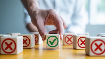 Hand picking a wooden block with a green check mark from a set of blocks with red crosses on a yellow table