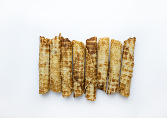 Rolled waffle cookies arranged in a neat row on a clean white background.