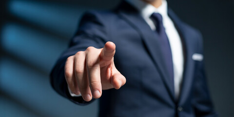 Fototapeta premium Businessman in dark suit pointing finger forward with blurred background 