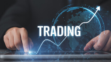 Businessman using tablet with TRADING text and global financial graph on dark background