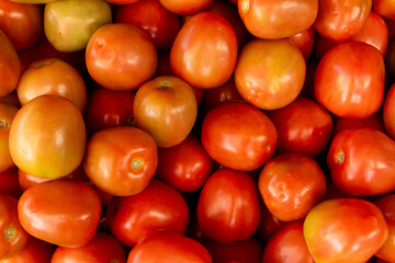 Ripe red juicy tomatoes displayed at a vibrant market stall, highlighting fresh tropical produce, healthy eating, and local market life
