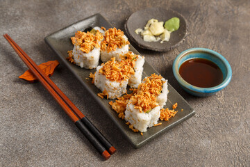 Crispy roll saumon avocat sur table foncée avec sauces soja, baguettes, vaisselle traditionnelle. Cuisine japonaise. 