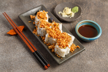 Crispy roll saumon avocat sur table foncée avec sauces soja, baguettes, vaisselle traditionnelle. Cuisine japonaise. 