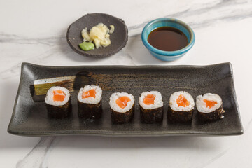 Maki saumon sur table en marbre e avec sauces soja, baguettes, vaisselle traditionnelle