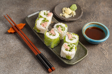 Spring rolls au thon sur table foncée avec sauces soja et baguettes
