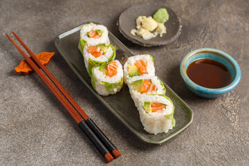 Spring rolls saumon avocat sur table foncée avec sauces soja et baguettes
