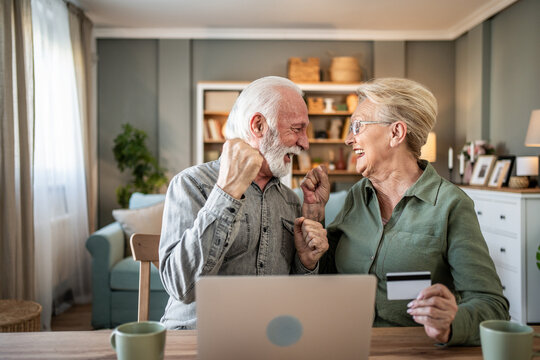 Senior couple celebrating successful online purchase with laptop