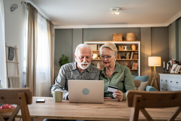 Senior couple shopping online using laptop and credit card