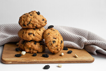 Close up photo stack cookies with scattered raisins and nuts on light background. Homemade baking. For article, blog and recipe.