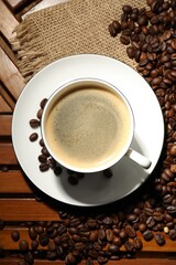 Aromatic coffee in cup and beans on wooden table, flat lay